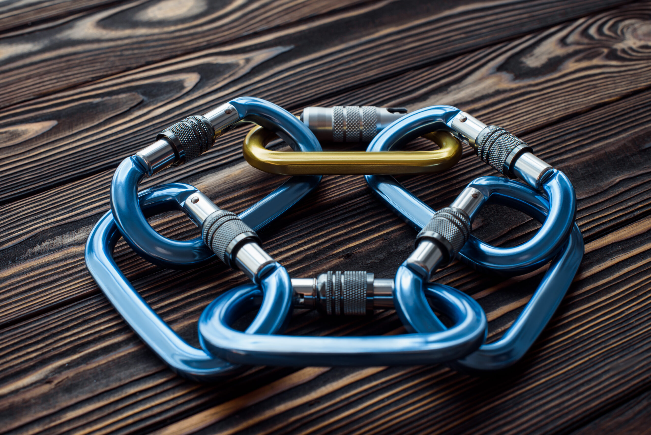 Rock climbing sports. Isolated photo of climbing equipment. Parts of carabiners lying on the wooden table