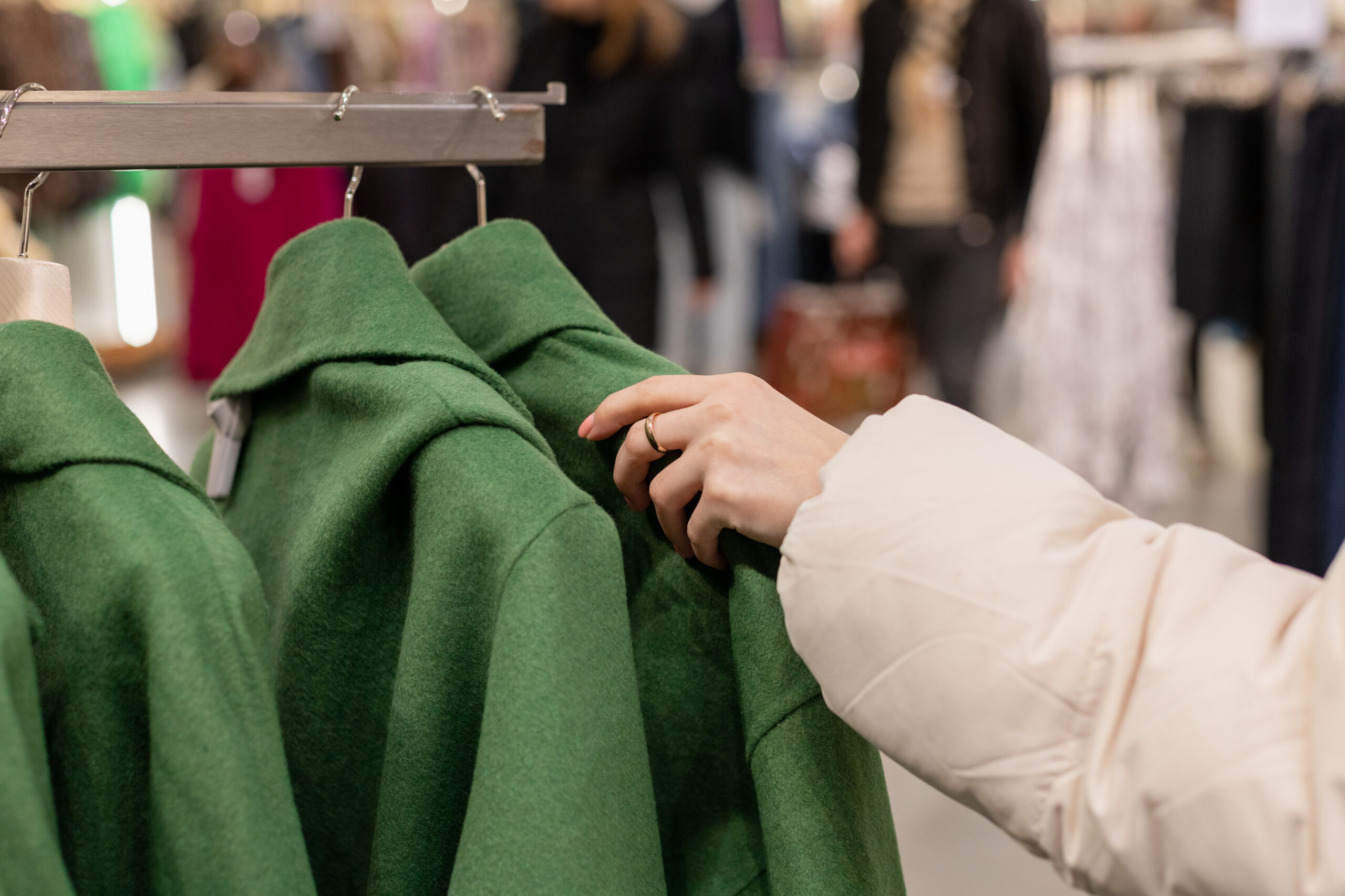 A young girl makes purchases in a clothing store, chooses women’s coats.