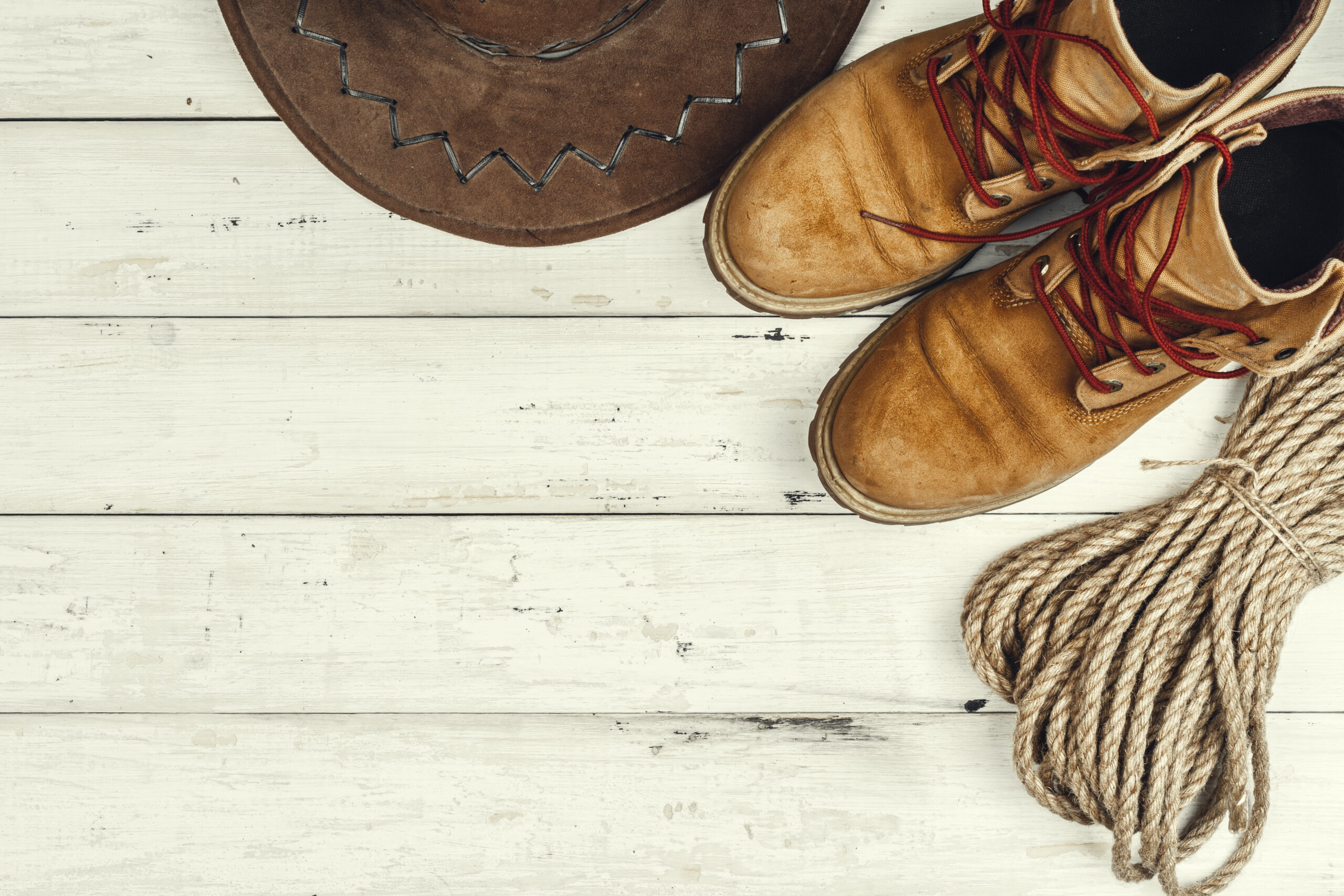 Hiking boots with travel accessories on grunge background